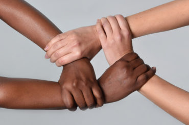 white Caucasian female hands and black African American holding together in world unity and racial love and understanding in tolerance and races diversity cooperation concept